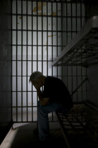 A man sitting in the dark in a jail cell