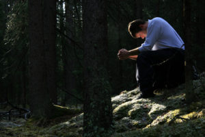 man praying in a quiet forest