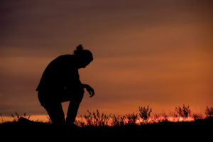 man kneeling at sunset