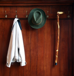 Jacket, hat and cane hanging from hangers after arriving home