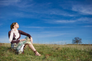 A woman sitting in a field with her eyes closed