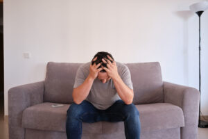 A man sitting on the couch with his head in his hands