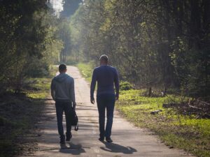 two people walking together on a path through the trees