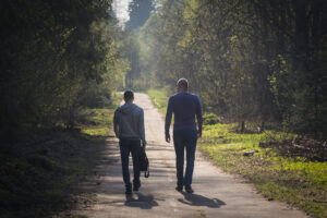 An older man and younger man walking together on a path.