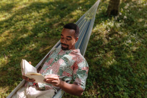 A man lying in a hammock reading