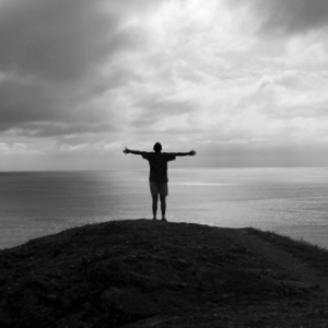 A man standing in front of the ocean with his arms wide open